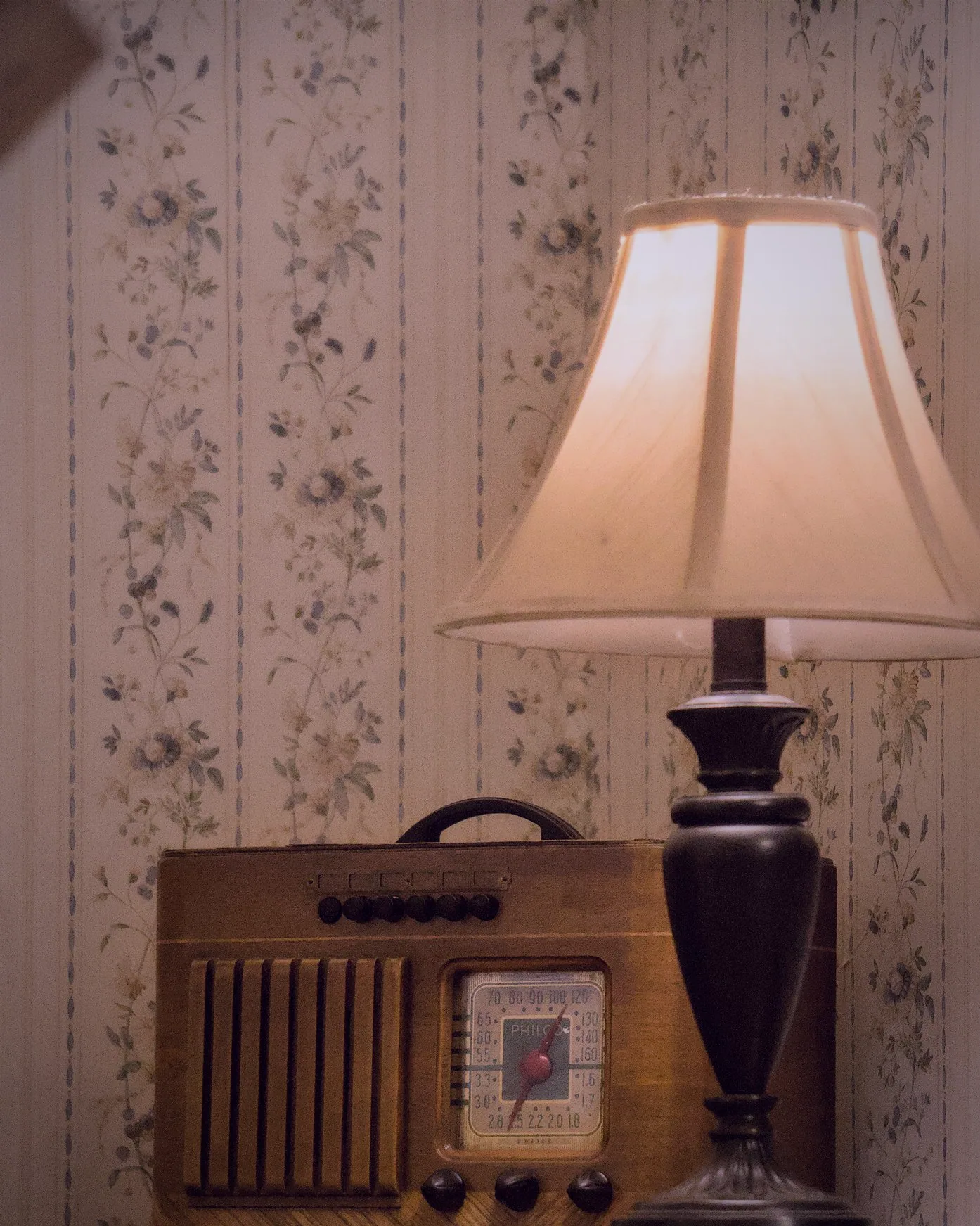 A lamp glowing against the floral wallpaper before the doors open