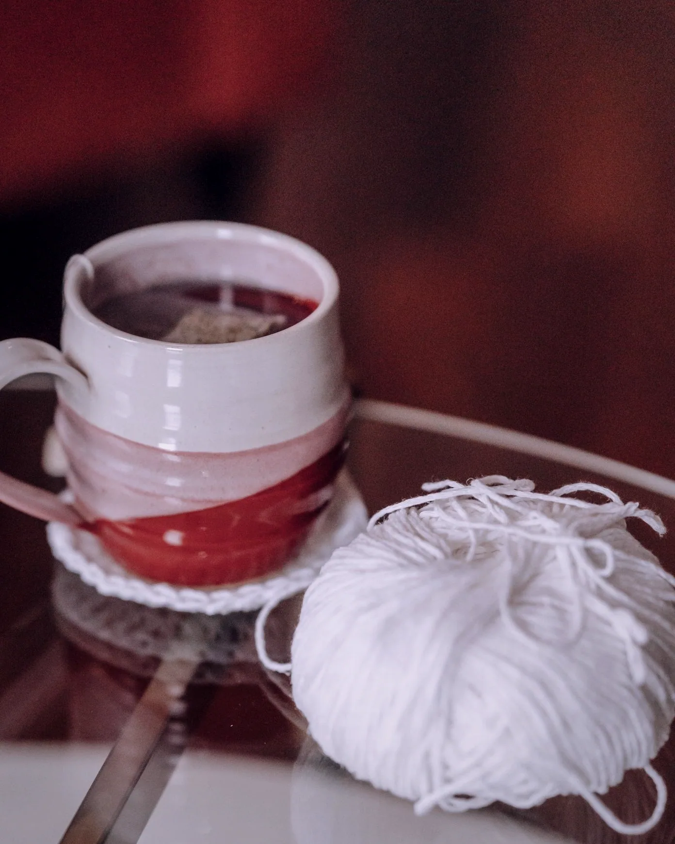 A glass of tea and a spoon set on the patterned cloth by the window